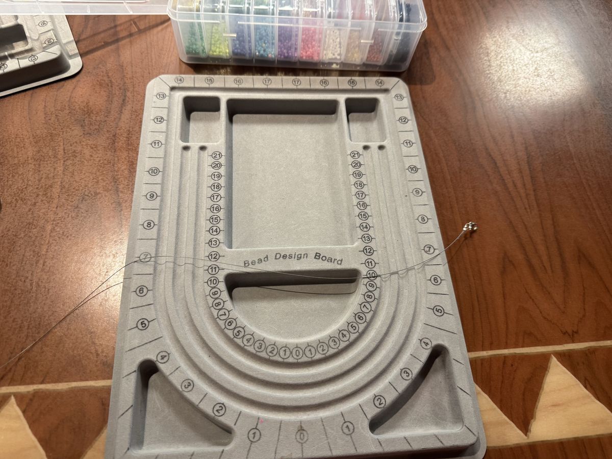 A bead design board and sorted boxes of beads for jewelry making