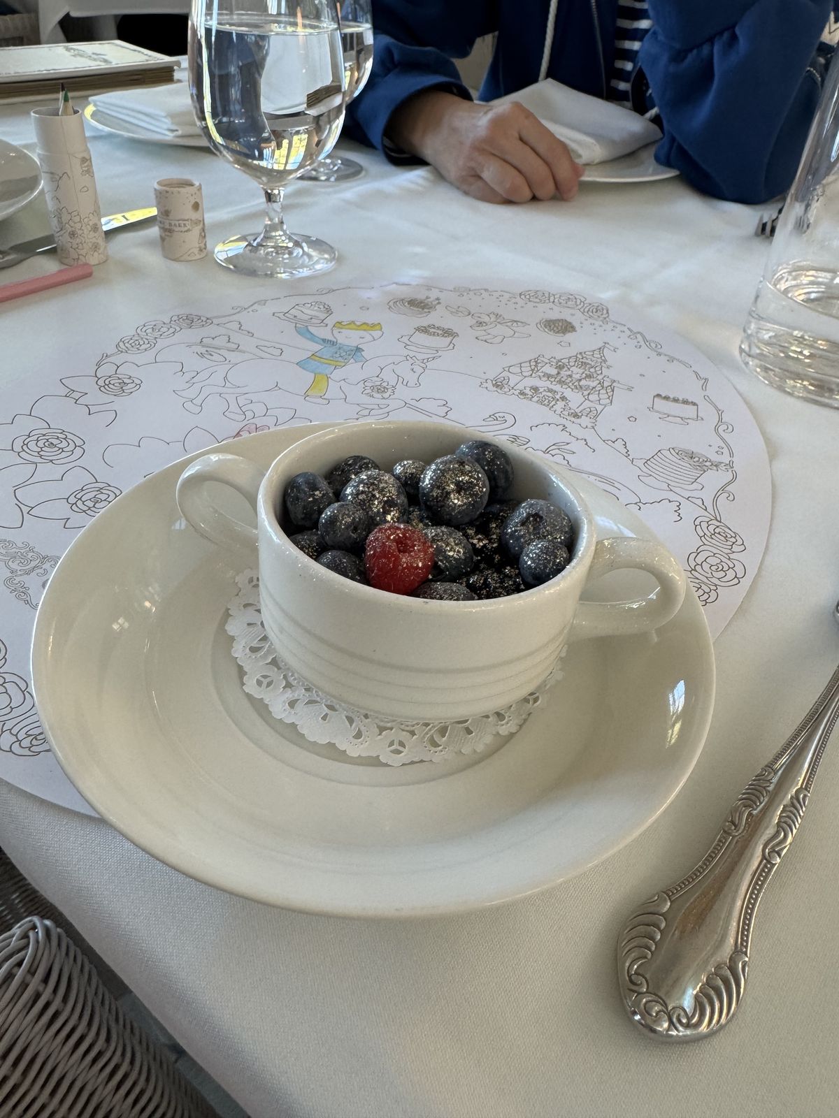 A bowl of blueberries and a raspberry dusted with edible glitter