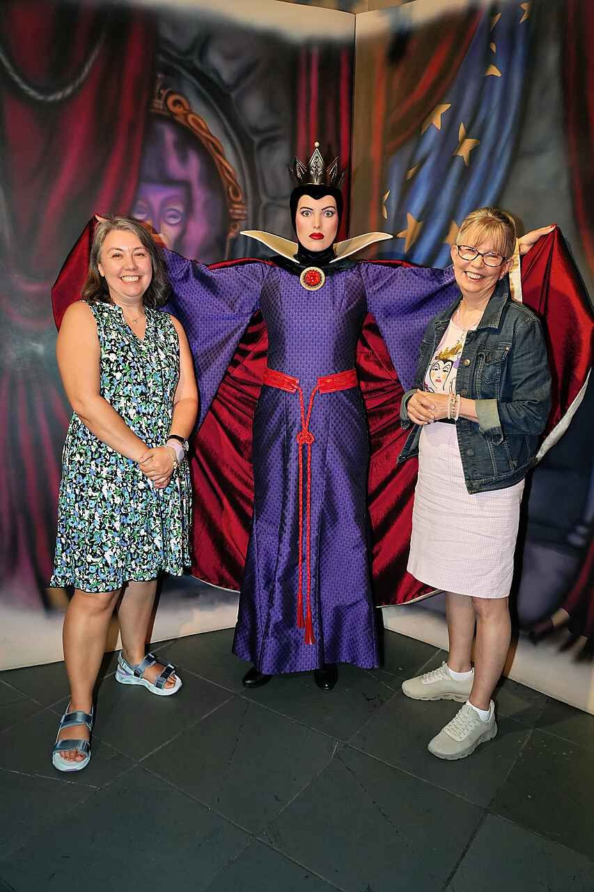 Vanessa and her mom posing with the Evil Queen, cape spread wide